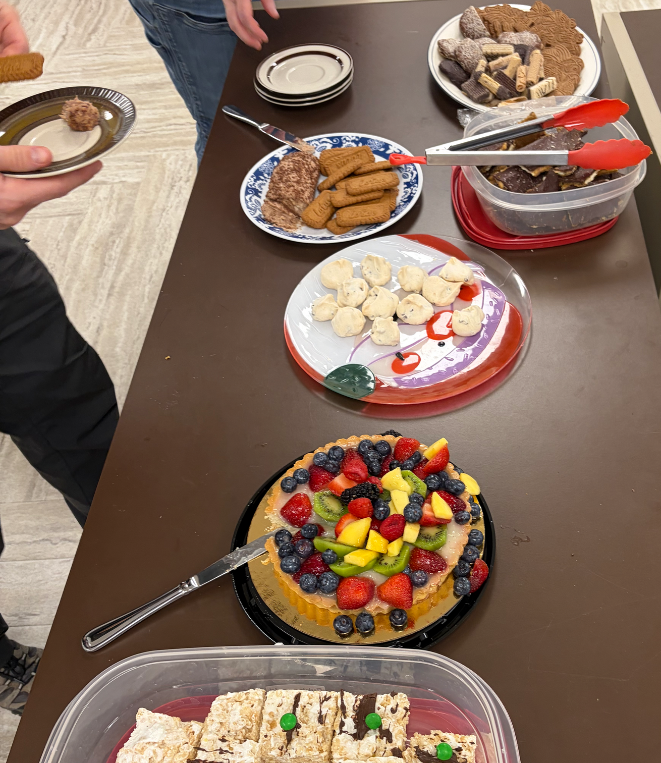 Another table with desserts: a fruit tart, meringues, cookies, rice crispies, saltine candies, and a chocolate spread.